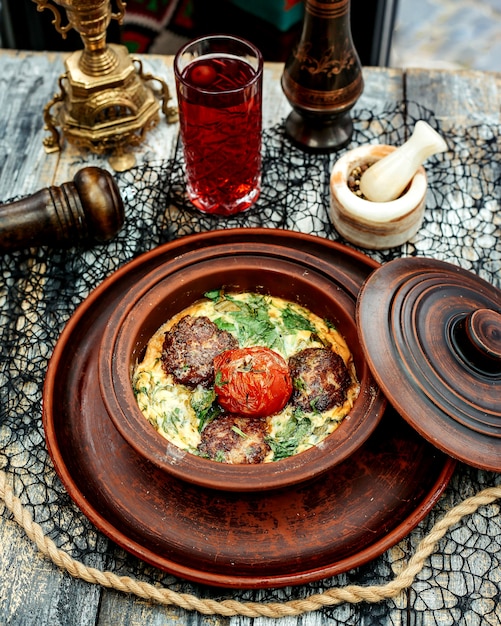 A pottery pan with meat balls cooked in egg with spinach