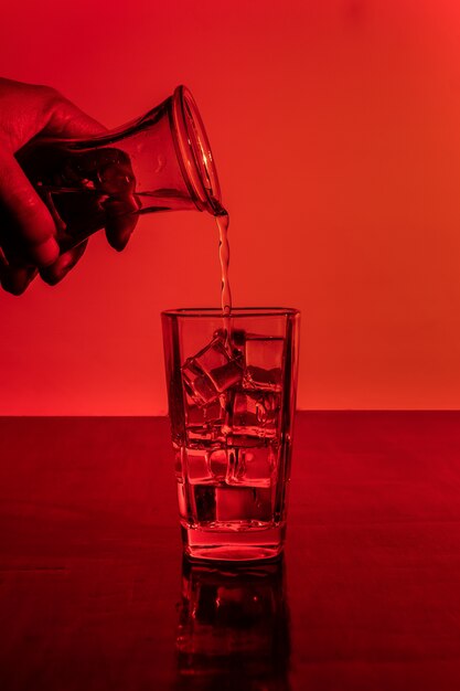 Заливка алкоголя в стакан, полный кубиков льда
