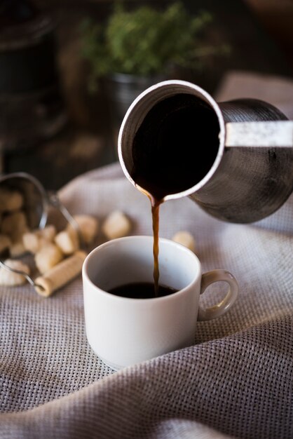 Pouring coffee from a kettle into a cup