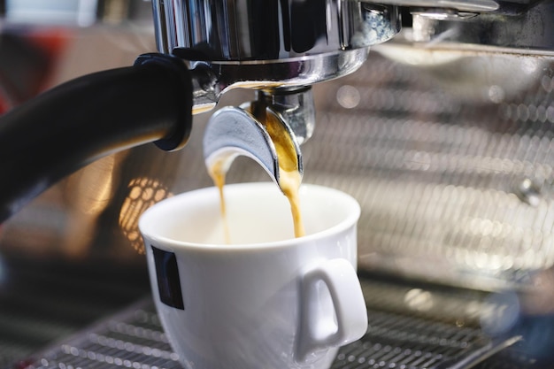 Pouring espresso in cup from machine