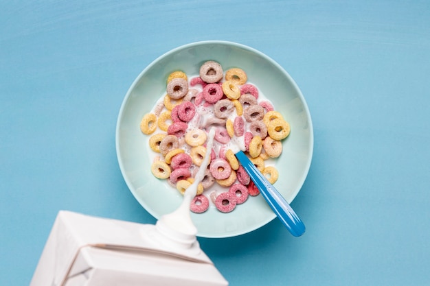 Free photo pouring fresh creamy milk into a bowl filled with cereals