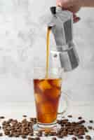 Free photo pouring iced coffee in glass