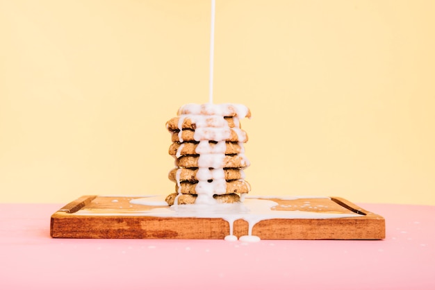 Pouring milk on cookies stack on wooden board