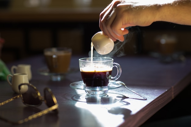 Pouring milk in a cup of coffee