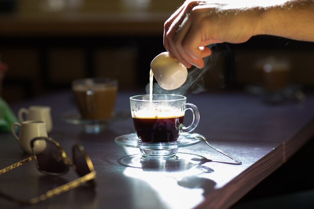 コーヒーのカップにミルクを注ぎます