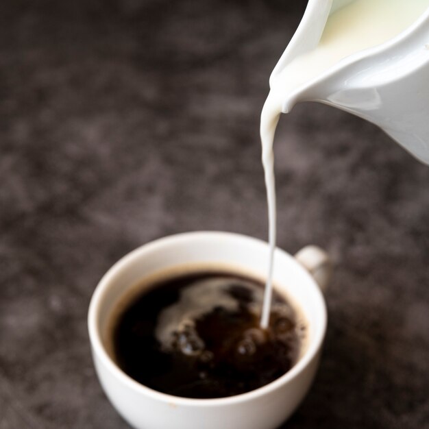 Наливая молоко в кофейную чашку