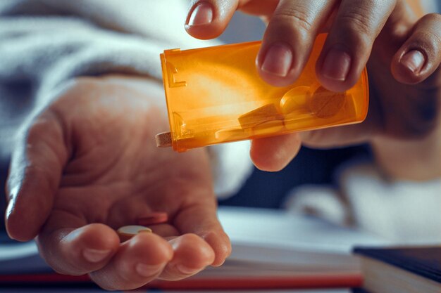 Pouring the pills from the orange bottle into the plam