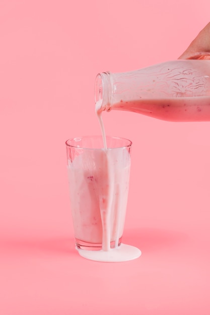 Pouring pink yogurt in glass