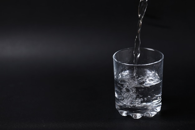 Pouring water into a half filled glass.