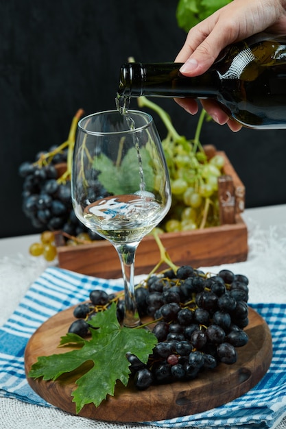 흰색 테이블에 포도 접시와 함께 유리에 와인을 붓는