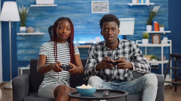 컨트롤러로 비디오 게임을 하는 흑인 커플의 POV