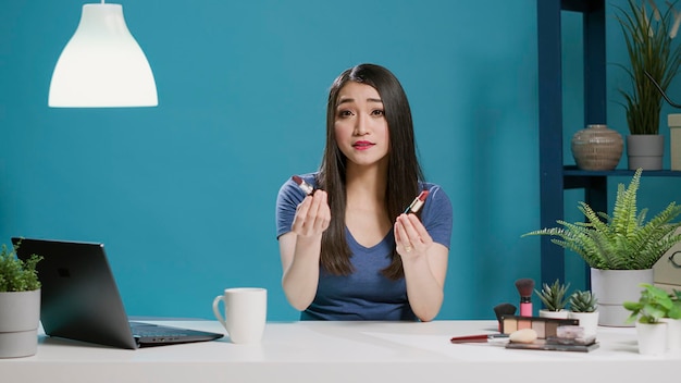 POV of content creator doing lipstick review on vlogging camera, recording online videoblog in studio. Female influencer recommending makeup product cosmetics on social media. Tripod shot.