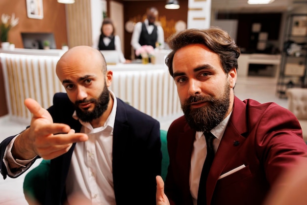 Free photo pov of diverse men in hotel lobby, meeting abroad to create new parnership and collaborate on project. team of businessmen attend videocall conference together in lounge area.