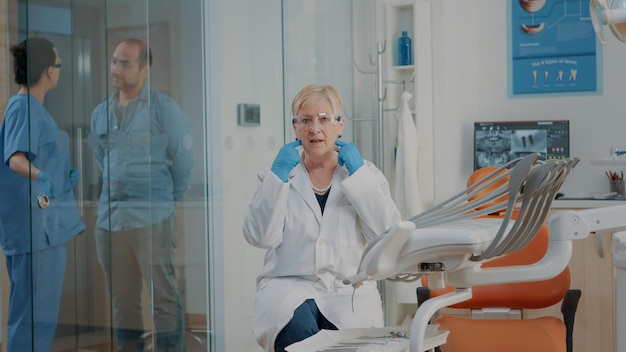 POV of mature dentist talking on video call with patient in dentistry cabinet at clinic. Stomatology specialist using online videoconference to have remote conversation for telecommunication.