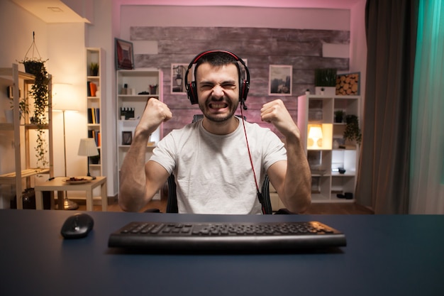 Pov of young man excited about his wining while playing shooter games on stream.