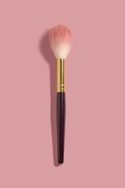 A powder makeup blush brush on pink background