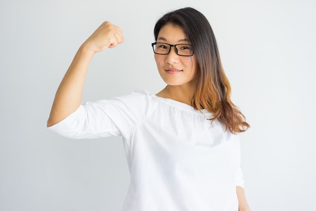 Powerful confident young Asian lady showing her muscle.