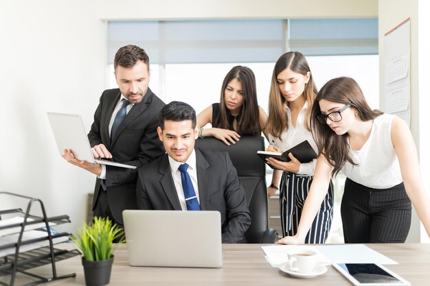 Powerful office workers watching presentation on laptop at desk in office