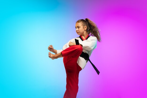 Practice. Karate, taekwondo girl with black belt isolated on gradient