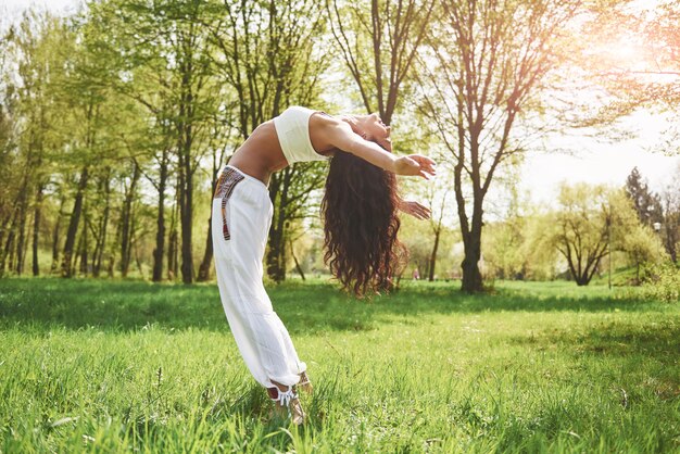 Практика йоги красивой девушки утром на травах под словами солнца.