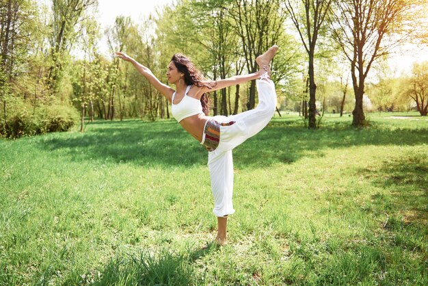 Практика йоги красивой девушки утром на травах под словами солнца.