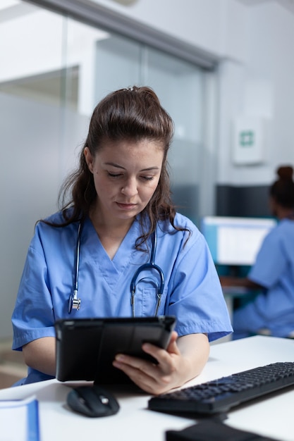 질병 전문 지식을 분석하는 태블릿 컴퓨터를 들고 개업 간호사