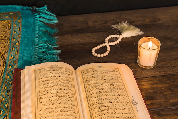 Prayer beads and candle near religious book