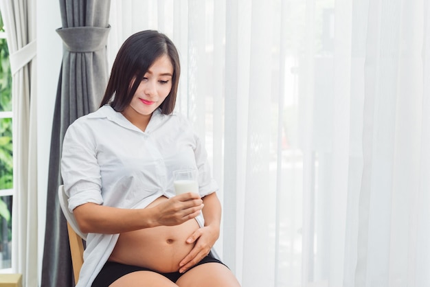 Беременная женщина держит стакан молока для питья