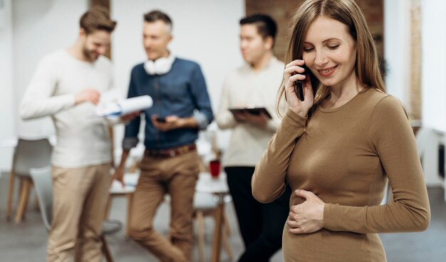 Pregnant businesswoman talking on the phone while touching her belly