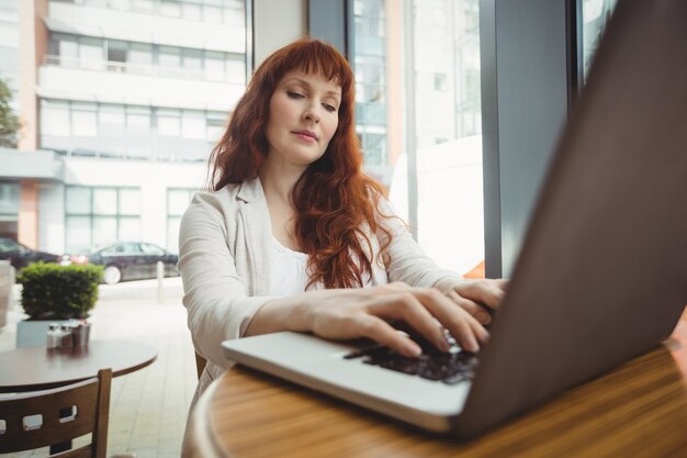 Pregnant businesswoman using laptop in cafeteria