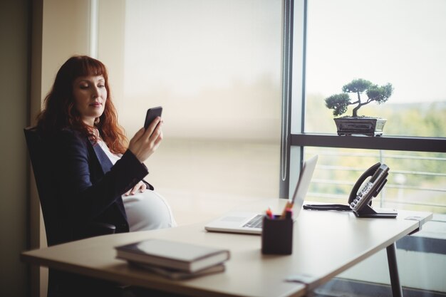 Pregnant businesswoman using mobile phone