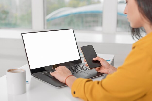 Pregnant businesswoman working on laptop with smartphone