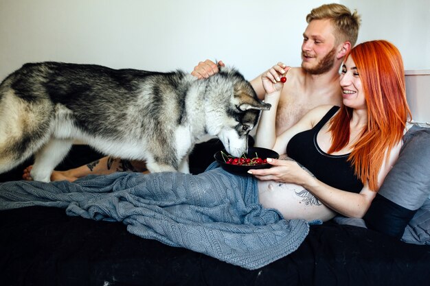 Pregnant couple with dog on bed