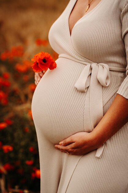 咲くケシ畑の中に立っている妊婦