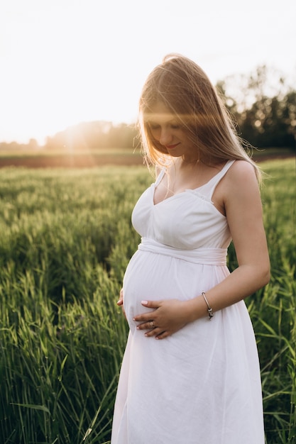 The pregnant girl stands on the fiield