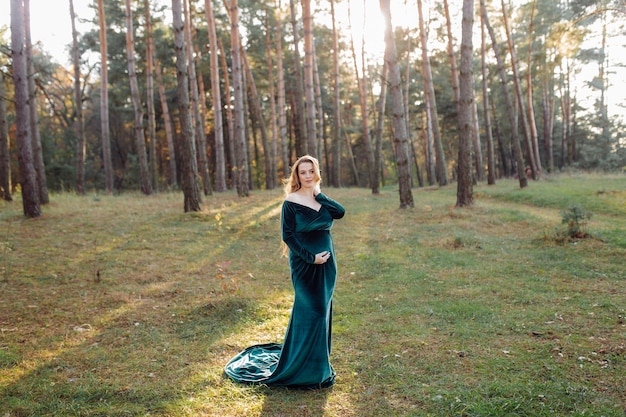 Pregnant happy young woman walking outdoors in forest