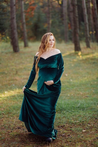 Pregnant happy young woman walking outdoors in forest