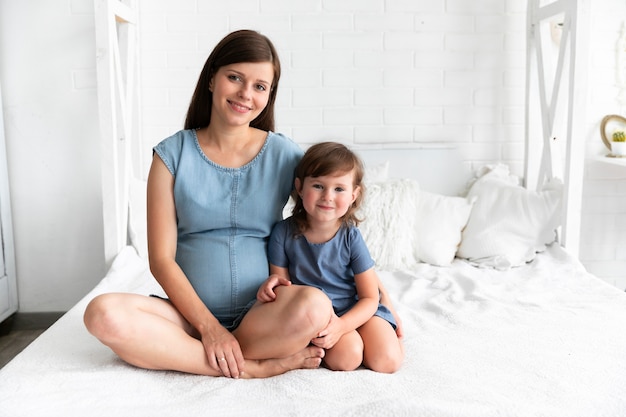 Foto gratuita madre incinta e figlia che esaminano la macchina fotografica