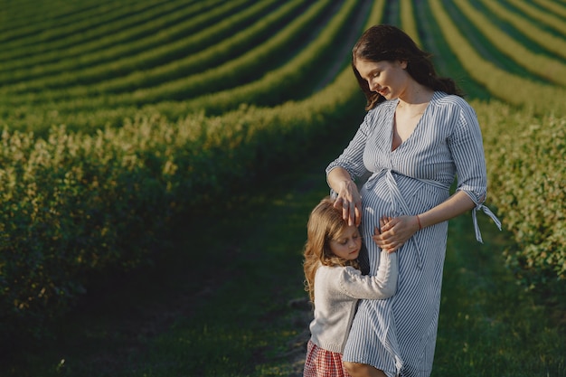 Free photo pregnant mother with her daughter in a field