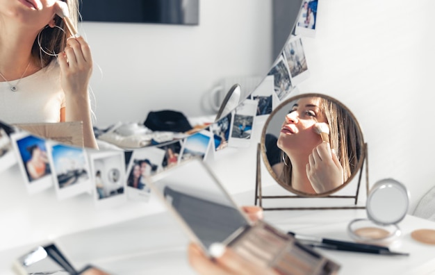 Беременная женщина наносит макияж дома перед зеркалом