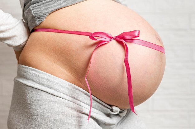 Pregnant woman belly with cute ribbon