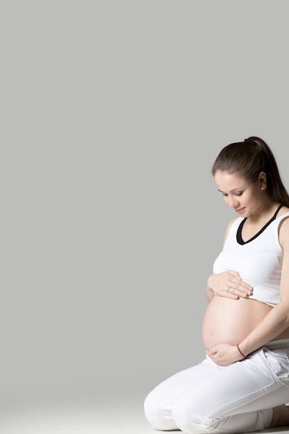 무료 사진 임신 한 여자는 그녀의 배꼽을 쥐고