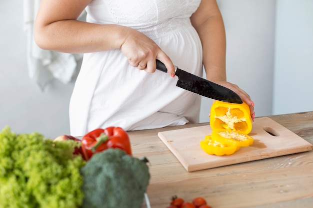 Free photo pregnant woman cutting vegetables