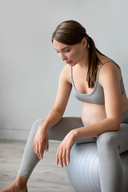 Беременная женщина, тренирующаяся дома