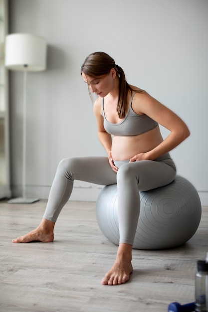 Sits on yoga mat. Woman with sportive slim body type in underwear