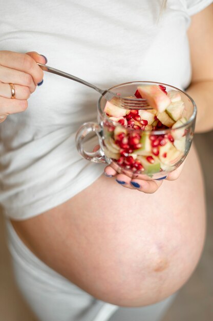 Pregnant woman hands holding a bowl of salad