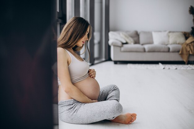 Pregnant woman having rest after exercising at home