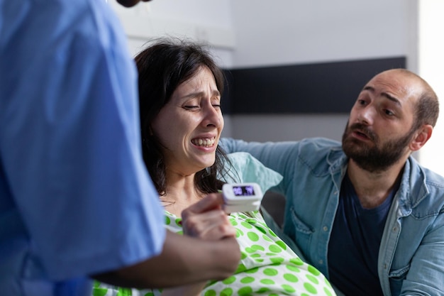 Free photo pregnant woman holding hand of nurse and husband in hospital ward, having painful contractions. patient with pregnancy getting into labor having medical assistance at healthcare facility. close up