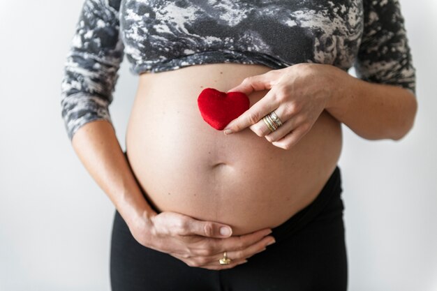 Pregnant woman holding a heart in front of her baby bump