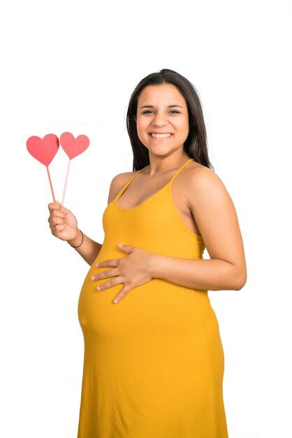 Беременная женщина, держащая знак сердца на животе